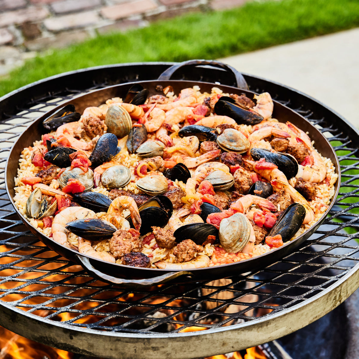 Seafood paella with mussels, clams and shrimp cooking in a Paella Pan over an open grill