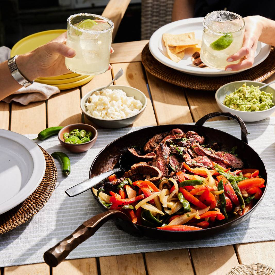 Steak fajitas with peppers and onions in a Deep Farmhouse Skillet on a patio table