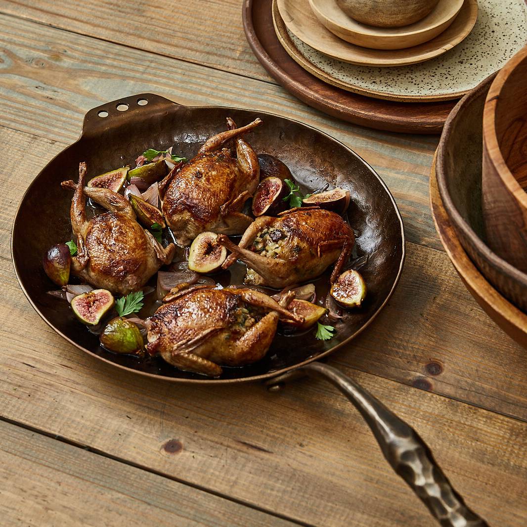 Roasted quail with figs and herbs in a Farmhouse Skillet on a wooden table