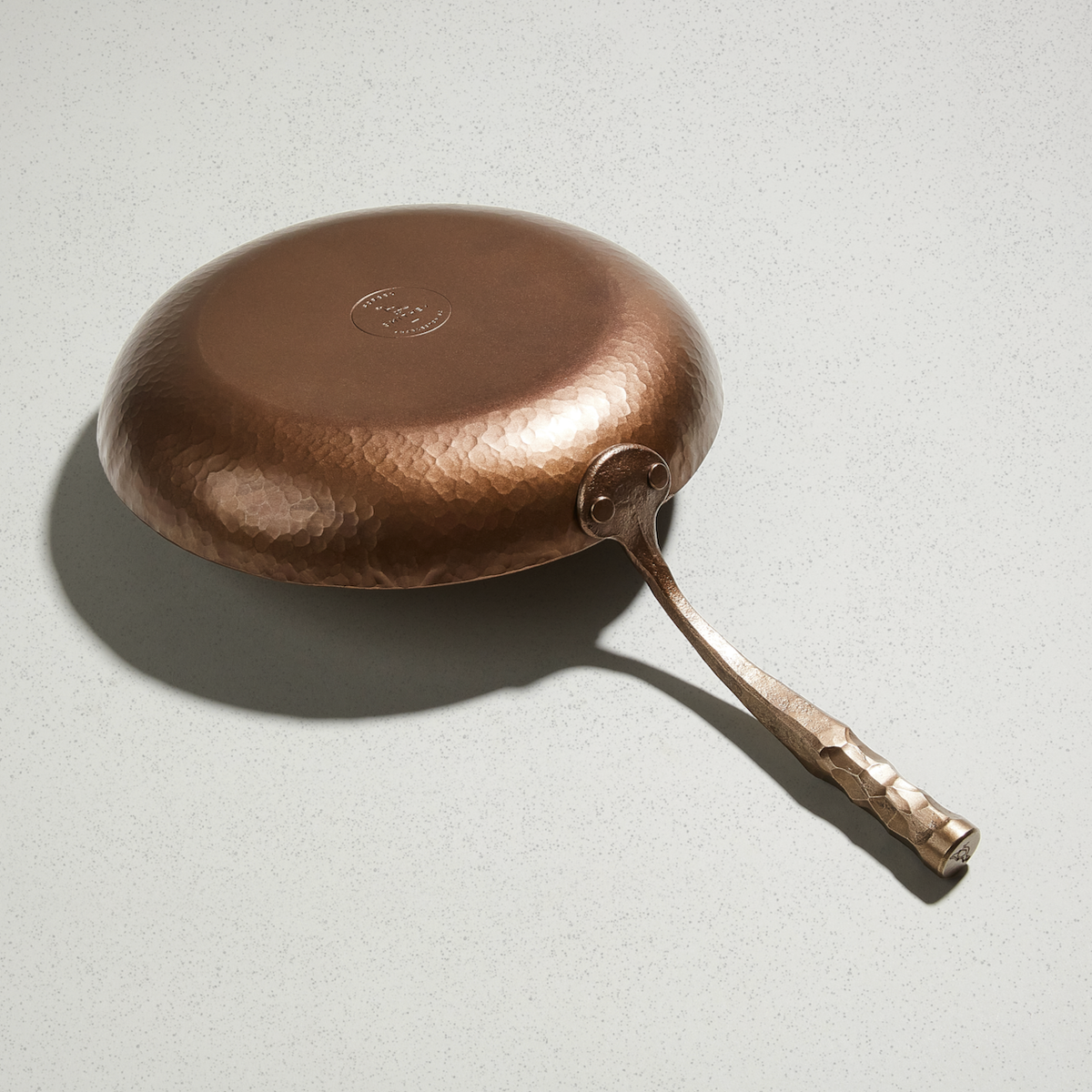 Underside of the Deep Farmhouse Skillet showing the hammered finish and Smithey logo