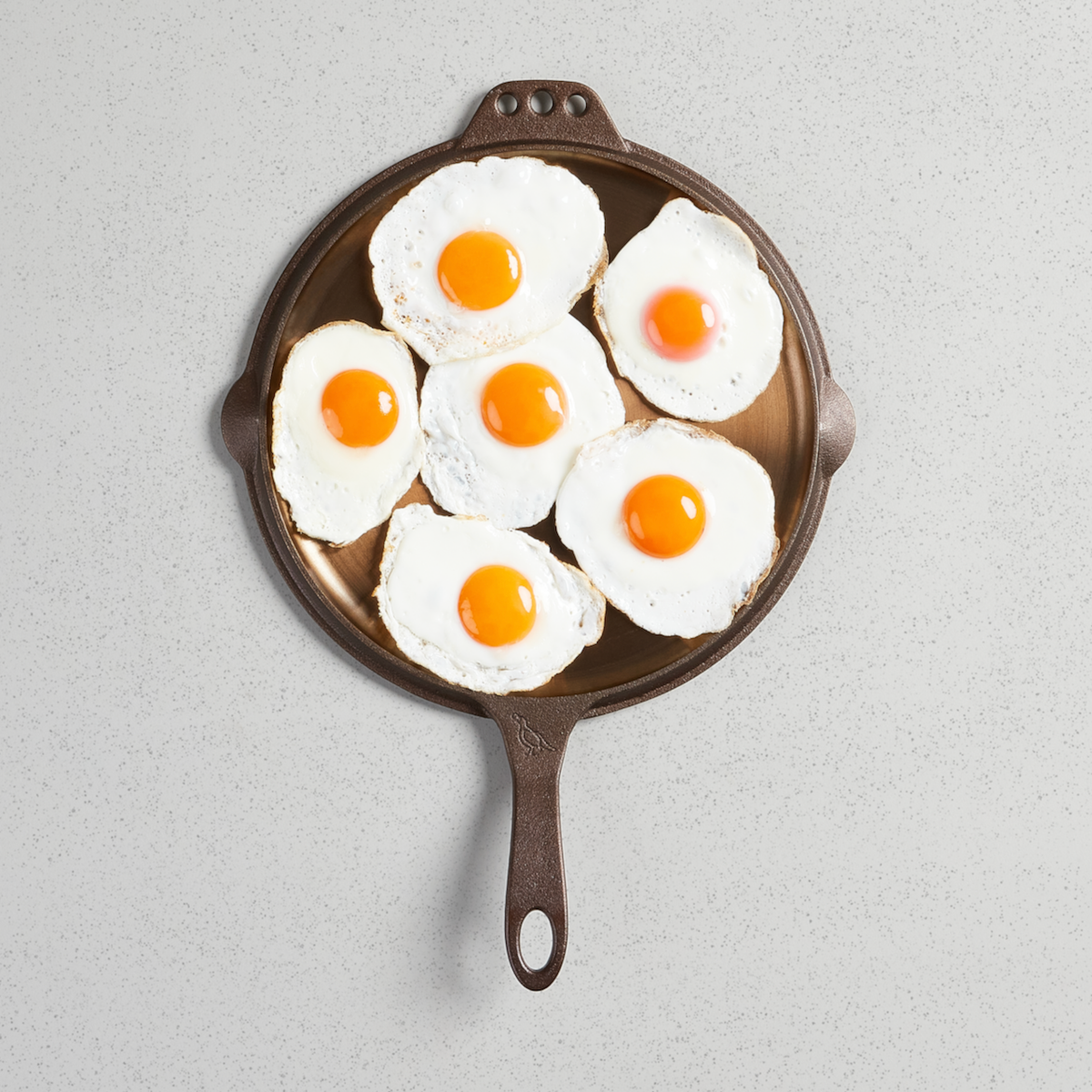 Seven fried eggs on a No. 12 Flat Top Griddle, viewed from above